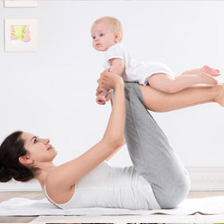 Young female in exercise clothing doing yoga with her baby